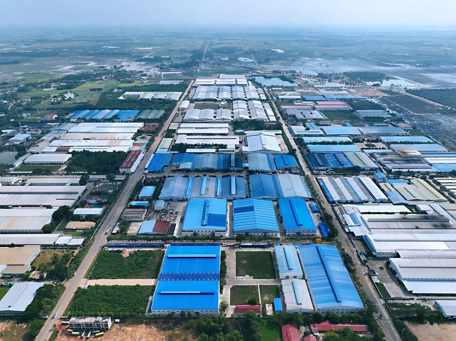 曼哈顿经济特区园区航拍，成排蓝色屋顶厂房沿园区道路排列