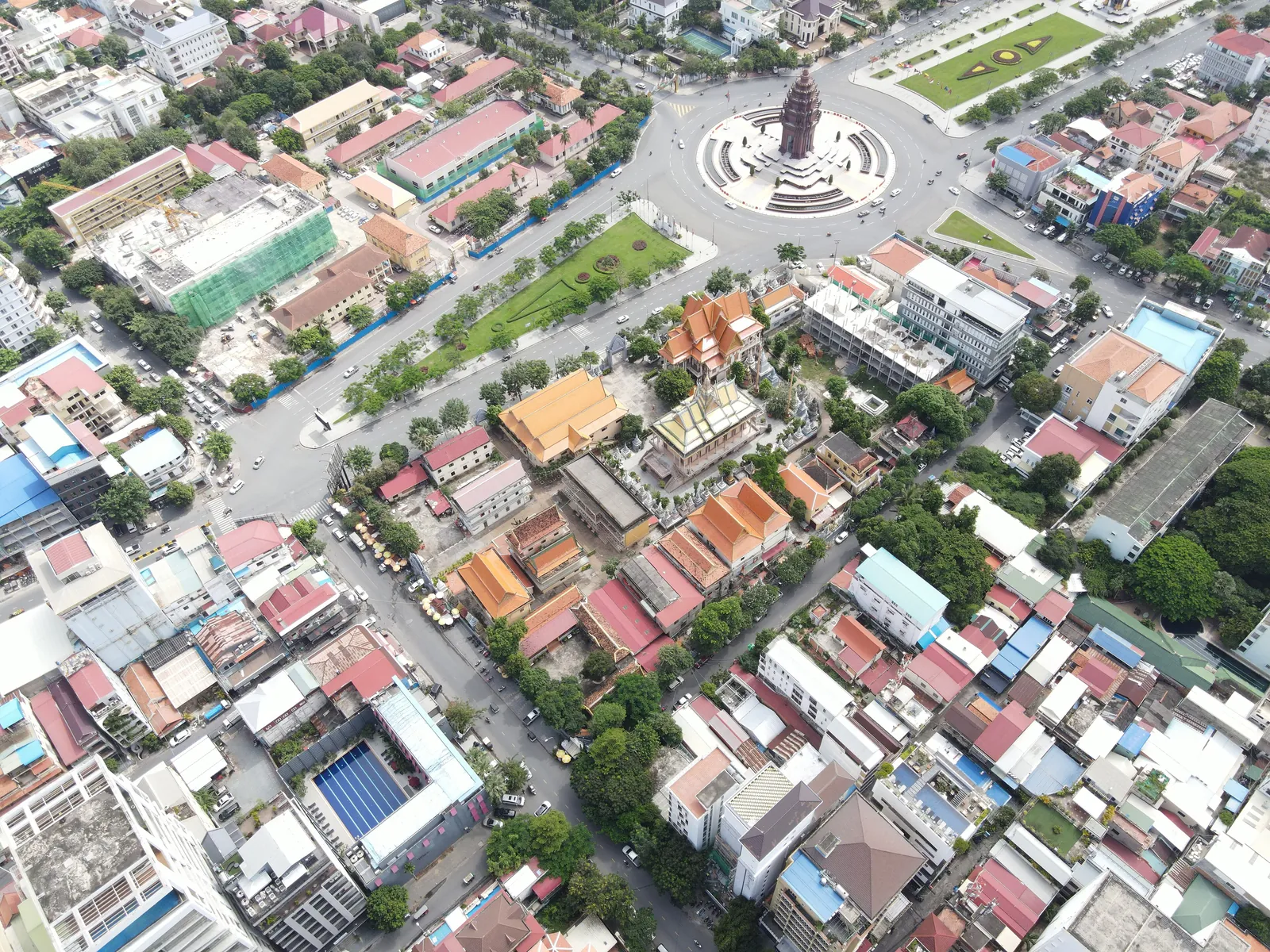 Aerial view of the roundabout around the Independence Monument in Phnom Penh, with surrounding streets and a Buddhist temple