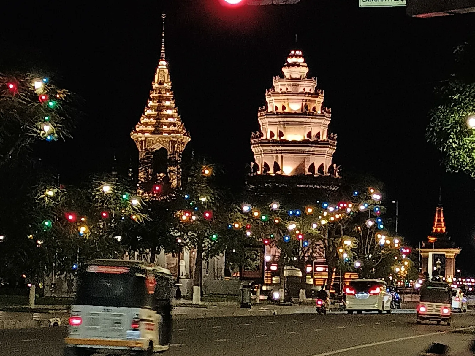 The Independence Monument in Phnom Penh lit up at night, seen from a street junction