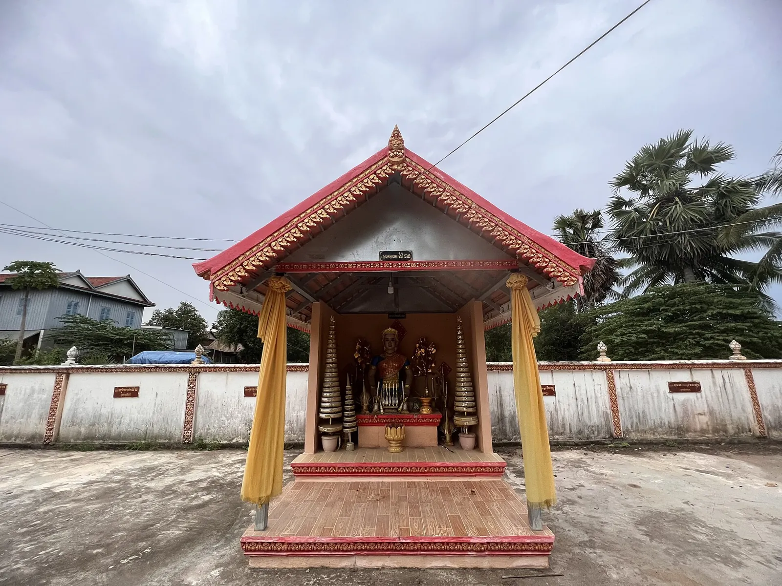 柬埔寨寺院院落中红色屋顶的神灵小屋与供桌